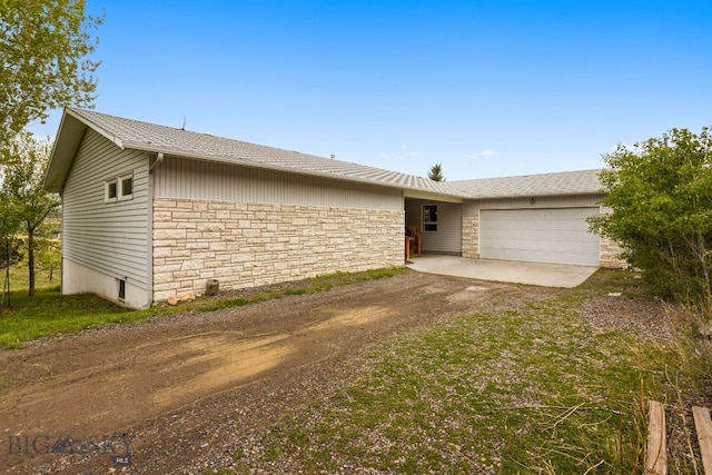 601 N C St, Livingston, MT 59047 - view of front of home with stone siding, an attached garage, and dirt driveway