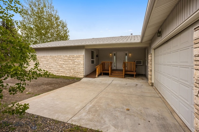 601 N C St, Livingston, MT 59047 - doorway to property with stone siding, an attached garage, driveway, and roof with shingles