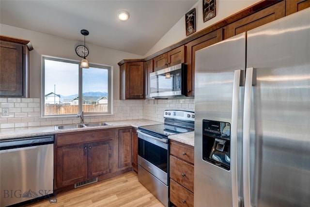 1510 Ingomar Blvd, Belgrade, MT 59714 - kitchen with appliances with stainless steel finishes, lofted ceiling, a sink, light wood-style flooring, and light countertops
