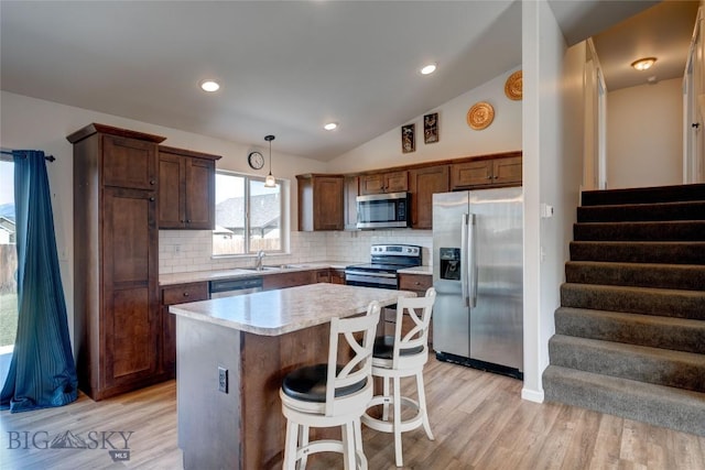 1510 Ingomar Blvd, Belgrade, MT 59714 - kitchen with stainless steel appliances, a center island, light countertops, backsplash, and light wood-style floors