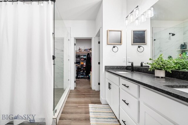 1506 Wild Bill Way, Belgrade, MT 59714 - bathroom featuring a shower stall, double vanity, wood finished floors, and a spacious closet