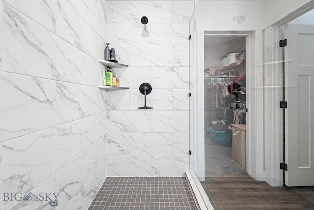 1506 Wild Bill Way, Belgrade, MT 59714 - full bathroom featuring a tile shower, a spacious closet, and wood finished floors