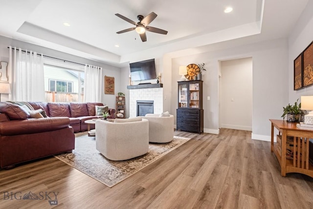 1506 Wild Bill Way, Belgrade, MT 59714 - living area with a raised ceiling, light wood-style flooring, a ceiling fan, a brick fireplace, and recessed lighting