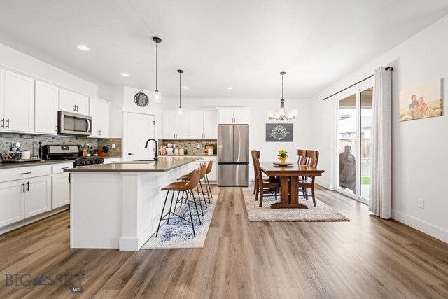 1506 Wild Bill Way, Belgrade, MT 59714 - kitchen with appliances with stainless steel finishes, dark countertops, a chandelier, backsplash, and light wood-style flooring
