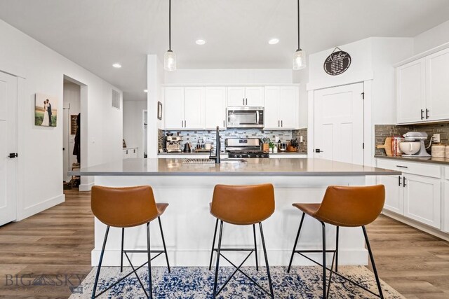1506 Wild Bill Way, Belgrade, MT 59714 - kitchen with appliances with stainless steel finishes, a sink, a breakfast bar area, decorative backsplash, and recessed lighting