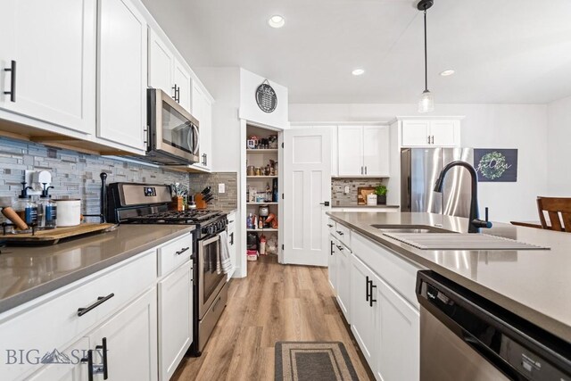 1506 Wild Bill Way, Belgrade, MT 59714 - kitchen with appliances with stainless steel finishes, a sink, tasteful backsplash, light wood-style floors, and white cabinets