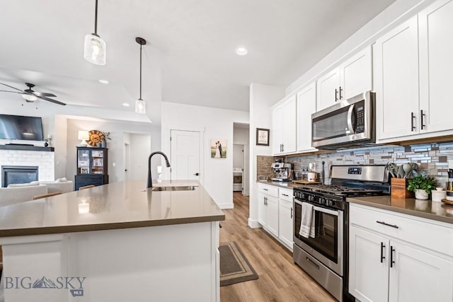 1506 Wild Bill Way, Belgrade, MT 59714 - kitchen with stainless steel appliances, a sink, tasteful backsplash, light wood-type flooring, and a ceiling fan