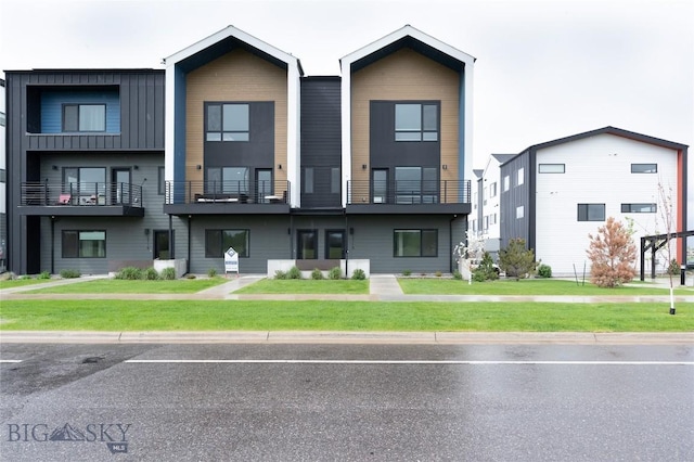 view of front facade with uncovered parking, a front yard, and board and batten siding