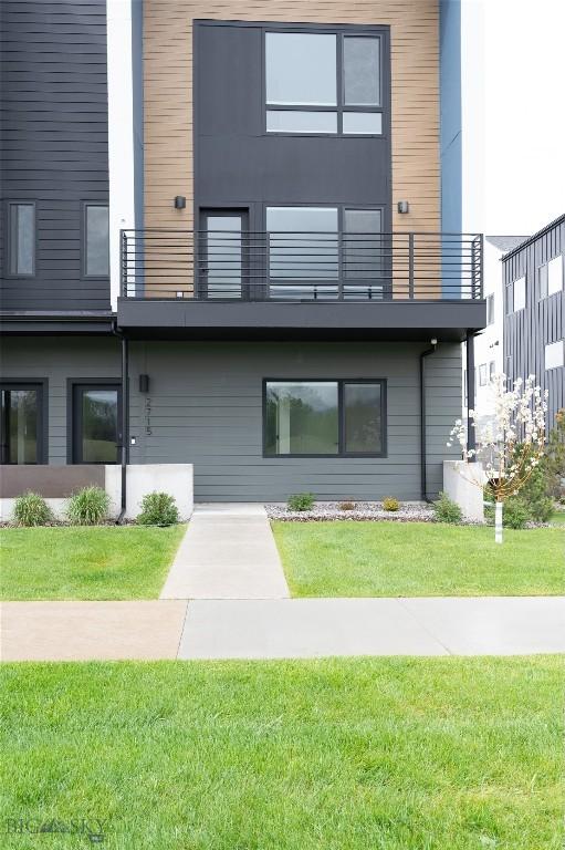 rear view of property with a balcony and a lawn