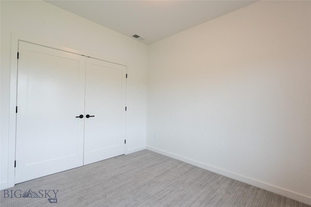 unfurnished bedroom with light carpet, baseboards, and a closet