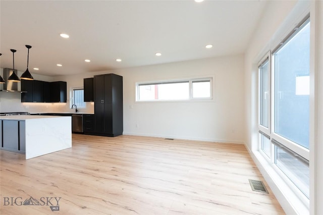 kitchen featuring extractor fan, dishwashing machine, light wood finished floors, recessed lighting, and a center island