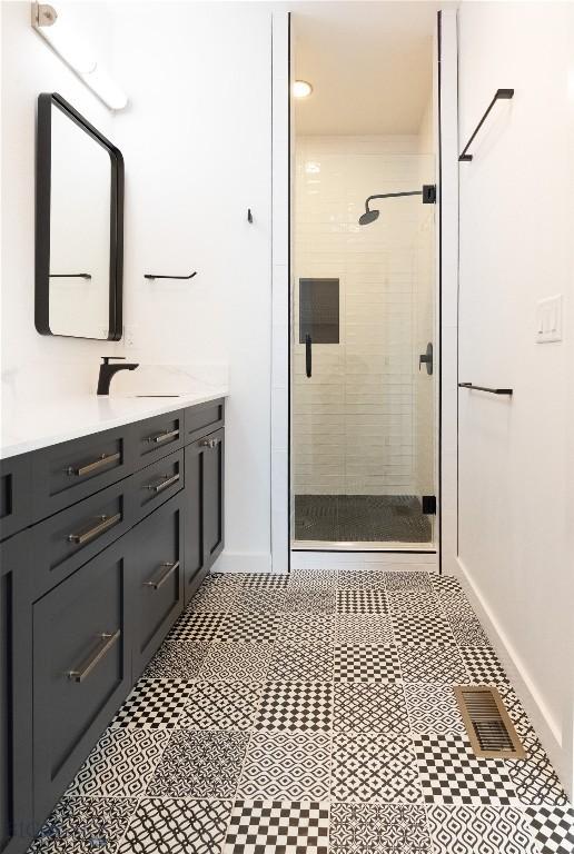 full bath with a shower stall, vanity, baseboards, and tile patterned floors