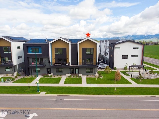 view of front of property with a front lawn and roof mounted solar panels