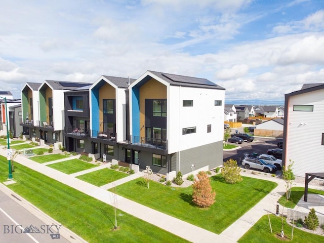 view of front of house with a residential view, a balcony, and a front yard