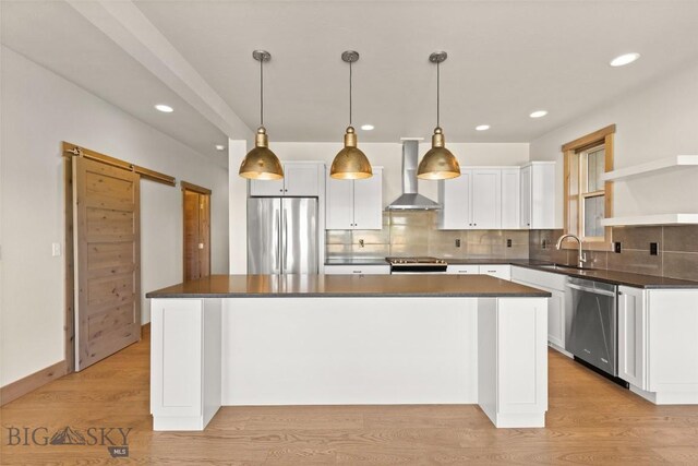 3164 S 15th Ave, Bozeman, MT 59715 - kitchen with appliances with stainless steel finishes, wall chimney exhaust hood, a sink, light wood-type flooring, and dark countertops
