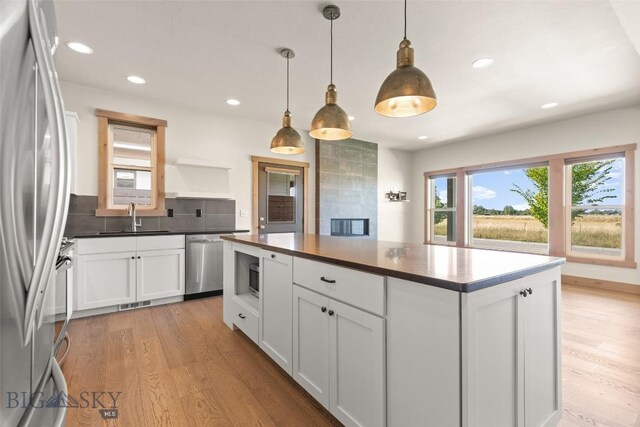 3164 S 15th Ave, Bozeman, MT 59715 - kitchen with appliances with stainless steel finishes, a sink, light wood finished floors, dark countertops, and white cabinetry