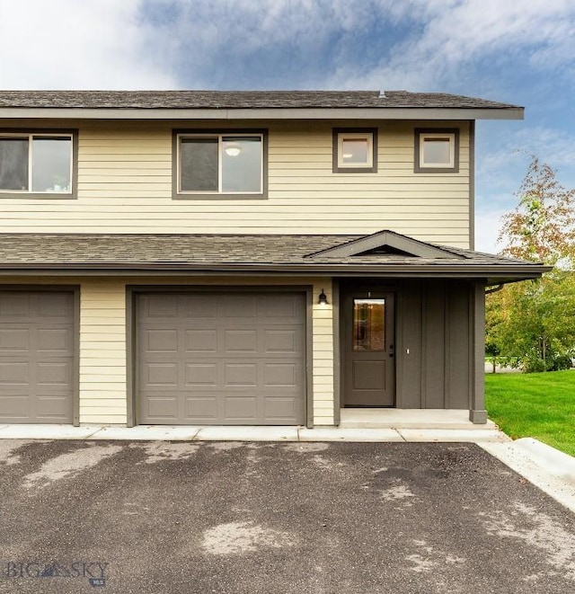 multi unit property with board and batten siding, a garage, and driveway