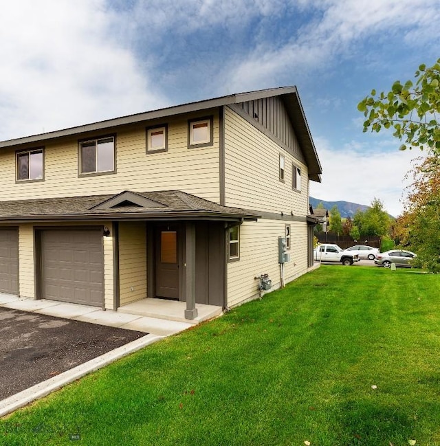 view of front of house with board and batten siding, a front lawn, a garage, driveway, and a mountain view