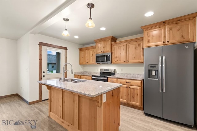 kitchen featuring stainless steel appliances, a sink, a center island with sink, light wood-type flooring, and light stone counters