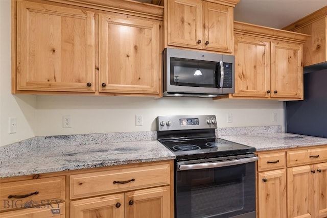 kitchen with appliances with stainless steel finishes, light brown cabinets, and light stone countertops