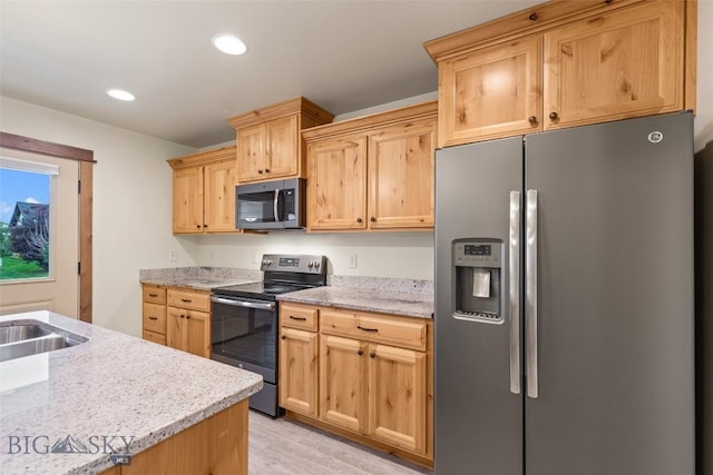 kitchen with stainless steel appliances, light wood-style flooring, light brown cabinets, a sink, and recessed lighting