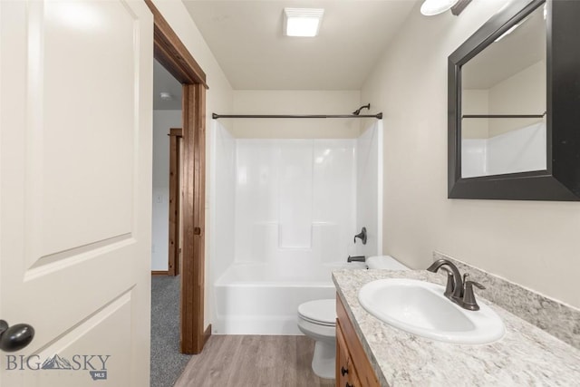 bathroom with toilet, wood finished floors, vanity, and tub / shower combination