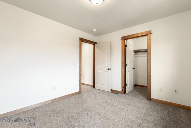 unfurnished bedroom with light colored carpet, baseboards, a walk in closet, and a closet