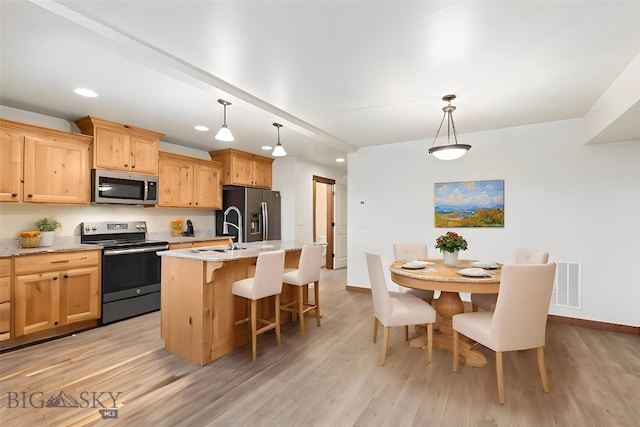 kitchen featuring stainless steel appliances, a sink, a kitchen island with sink, recessed lighting, and baseboards