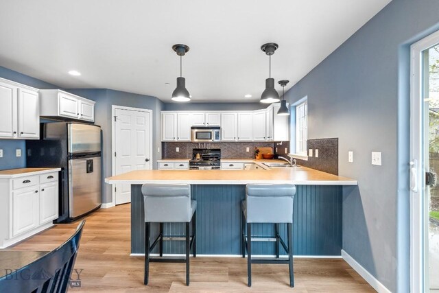 185 Chestnut Grove Ave, Bozeman, MT 59718 - kitchen featuring appliances with stainless steel finishes, a peninsula, decorative backsplash, white cabinetry, and recessed lighting