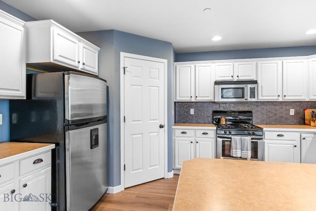 185 Chestnut Grove Ave, Bozeman, MT 59718 - kitchen featuring stainless steel appliances, light wood-style floors, white cabinets, light countertops, and backsplash