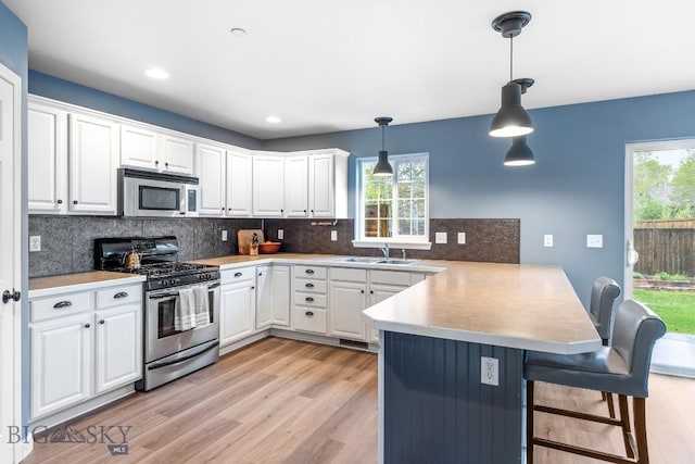 185 Chestnut Grove Ave, Bozeman, MT 59718 - kitchen featuring appliances with stainless steel finishes, a peninsula, a sink, white cabinets, and tasteful backsplash