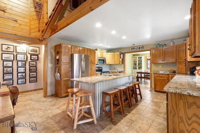 486 Jardine Rd, Jardine, MT 59030 - kitchen with stainless steel appliances, a sink, decorative backsplash, an island with sink, and light stone counters
