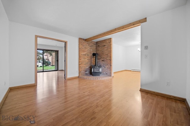 unfurnished living room with baseboard heating, light wood-type flooring, a wood stove, baseboards, and beamed ceiling