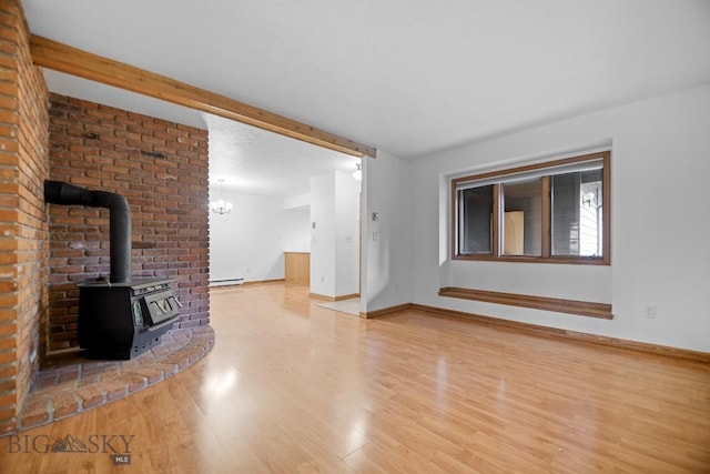unfurnished living room with wood finished floors, a wood stove, baseboards, baseboard heating, and a chandelier