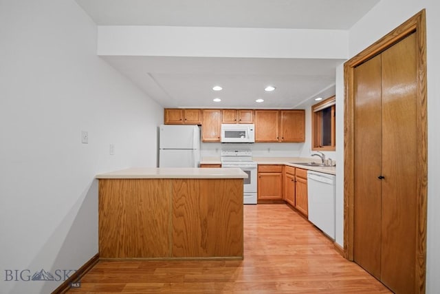 kitchen with white appliances, a peninsula, recessed lighting, light wood-type flooring, and a sink