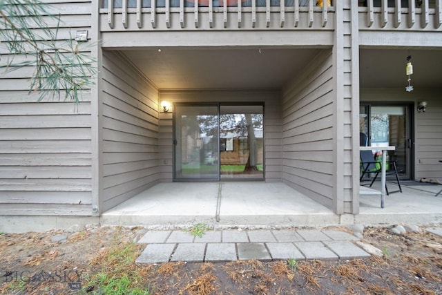 view of exterior entry featuring a patio and a balcony