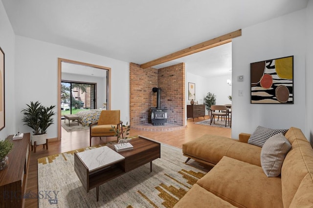 living room featuring a wood stove, wood finished floors, and beam ceiling