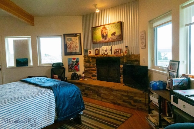 202 Beach Dr, West Yellowstone, MT 59758 - bedroom featuring a stone fireplace, wood finished floors, and beamed ceiling