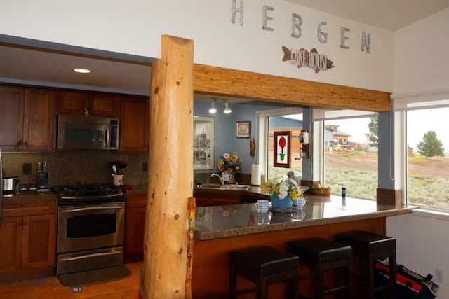 202 Beach Dr, West Yellowstone, MT 59758 - kitchen with appliances with stainless steel finishes, a sink, backsplash, a kitchen breakfast bar, and recessed lighting