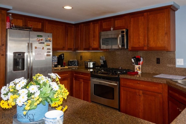 202 Beach Dr, West Yellowstone, MT 59758 - kitchen featuring appliances with stainless steel finishes, decorative backsplash, brown cabinets, and recessed lighting