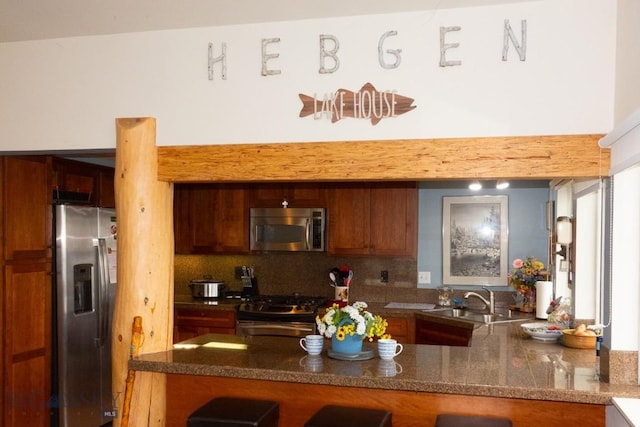 202 Beach Dr, West Yellowstone, MT 59758 - kitchen featuring appliances with stainless steel finishes, a sink, decorative backsplash, a peninsula, and dark stone countertops