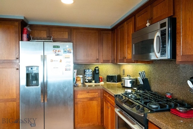 202 Beach Dr, West Yellowstone, MT 59758 - kitchen with stainless steel appliances, brown cabinetry, and backsplash