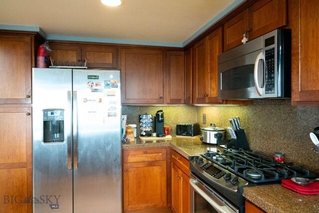 202 Beach Dr, West Yellowstone, MT 59758 - kitchen featuring appliances with stainless steel finishes, brown cabinets, and backsplash