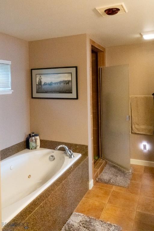 202 Beach Dr, West Yellowstone, MT 59758 - bathroom with a shower stall, a bath, and tile patterned flooring