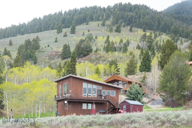 202 Beach Dr, West Yellowstone, MT 59758 - back of house with stairway, a forest view, and a deck