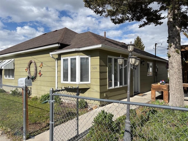 330 N Walnut St, Dillon, MT 59725 - view of home's exterior featuring a fenced front yard and roof with shingles