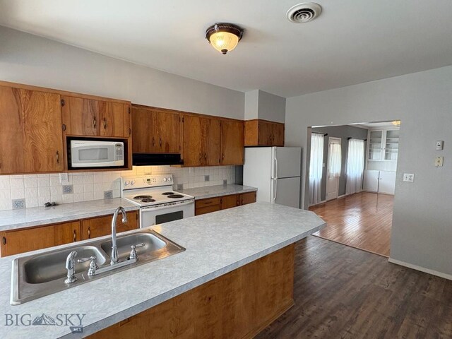 330 N Walnut St, Dillon, MT 59725 - kitchen featuring white appliances, under cabinet range hood, brown cabinetry, and a sink