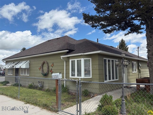 330 N Walnut St, Dillon, MT 59725 - view of home's exterior with a fenced front yard, a shingled roof, and a gate