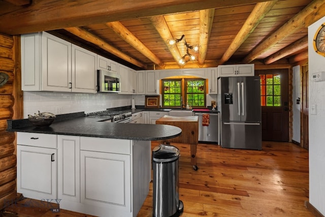 25 Big Chief Trl, Bozeman, MT 59718 - kitchen featuring stainless steel appliances, a wooden ceiling with exposed beams, dark countertops, healthy amount of natural light, and hardwood / wood-style flooring