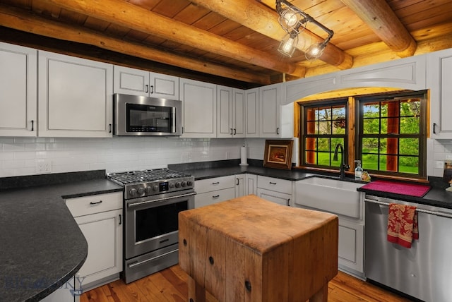 25 Big Chief Trl, Bozeman, MT 59718 - kitchen featuring stainless steel appliances, a wood ceiling with exposed beams, light wood finished floors, white cabinetry, and tasteful backsplash